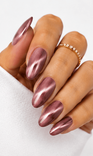 Cat-eye nails use magnetic gel to create a luminous line or velvet-like glow that shifts when the hands move. The effect resembles the reflective depth of a gemstone or a cat’s eye, giving the manicure a mysterious and elegant finish. This style is popular because it looks dimensional without needing complicated hand-painted art. It can be dramatic with dark jewel tones, romantic with pink and champagne shades, or soft and wearable with nude magnetic gels. Cat-eye nails are especially strong for salon photo collections because the light movement makes each angle look slightly different and luxurious.