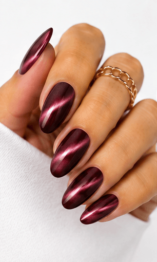 Cat-eye nails use magnetic gel to create a luminous line or velvet-like glow that shifts when the hands move. The effect resembles the reflective depth of a gemstone or a cat’s eye, giving the manicure a mysterious and elegant finish. This style is popular because it looks dimensional without needing complicated hand-painted art. It can be dramatic with dark jewel tones, romantic with pink and champagne shades, or soft and wearable with nude magnetic gels. Cat-eye nails are especially strong for salon photo collections because the light movement makes each angle look slightly different and luxurious.