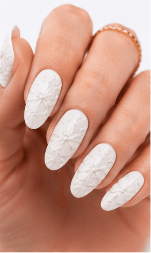 Emboss nails create raised patterns that look pressed, carved, or sculpted into the manicure surface. Unlike large 3D charms, emboss designs are usually more integrated with the nail and often appear as raised flowers, lace, shells, knit textures, monograms, ribbons, or ornamental lines. This style feels refined because the texture can be subtle while still adding depth and craftsmanship. White emboss over nude or milky bases looks bridal and elegant, while metallic or dark emboss can feel vintage, gothic, or fashion-forward. It is useful for luxury nail collections, wedding menus, winter knit designs, and close-up beauty photography.