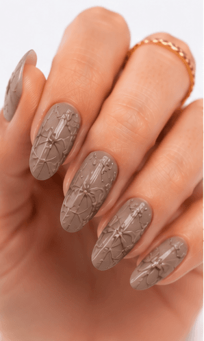Emboss nails create raised patterns that look pressed, carved, or sculpted into the manicure surface. Unlike large 3D charms, emboss designs are usually more integrated with the nail and often appear as raised flowers, lace, shells, knit textures, monograms, ribbons, or ornamental lines. This style feels refined because the texture can be subtle while still adding depth and craftsmanship. White emboss over nude or milky bases looks bridal and elegant, while metallic or dark emboss can feel vintage, gothic, or fashion-forward. It is useful for luxury nail collections, wedding menus, winter knit designs, and close-up beauty photography.